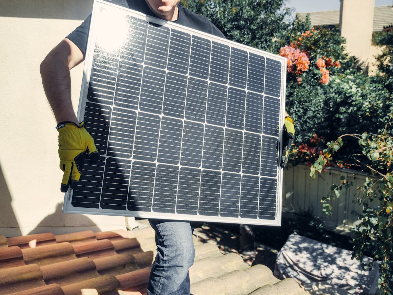 who-we-are Technician carrying solar panel on rooftop. Clean energy installation outdoors.